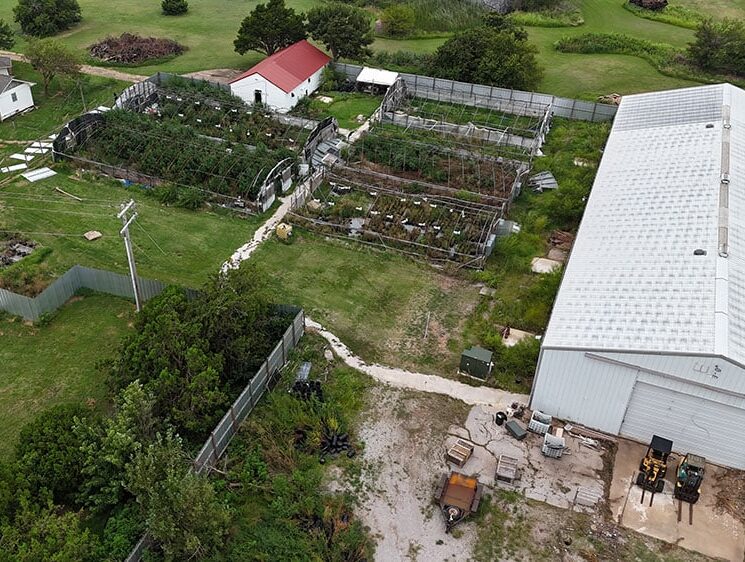 Aerial view of greenhouses and metal farm buildings.