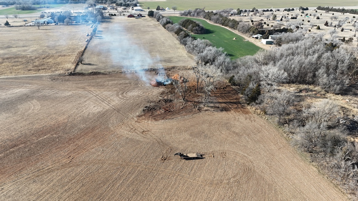 Aerial view of farm fields being cleared with a brush fire.